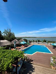 a swimming pool with chairs and umbrellas and the ocean at Casa cu Stuf Olimp in Olimp