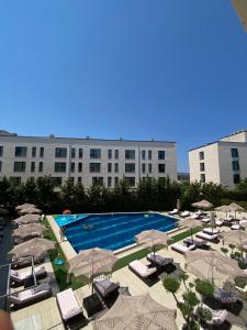 a swimming pool with chairs and umbrellas and a building at Duki's Apartments in Orikum