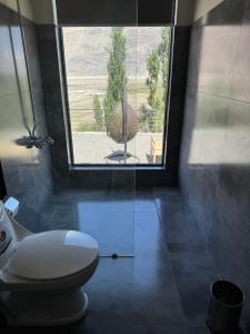 a bathroom with a toilet and a large window at Lamhay Private lodges in Skardu +20 photos
