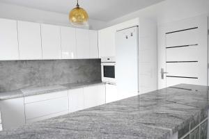 a kitchen with white cabinets and a marble counter top at U Edzia in Kochoń