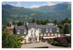 una gran casa blanca con montañas en el fondo en Hôtel du Soleil Levant, en Argelès-Gazost