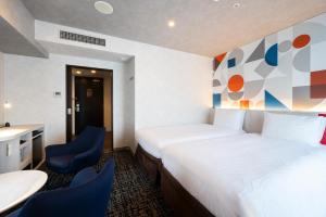 a hotel room with a bed and two blue chairs at Richmond Hotel Namba Daikokucho in Osaka