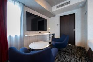 a hotel room with two blue chairs and a tv at Richmond Hotel Namba Daikokucho in Osaka