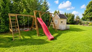 a playground with a slide and a house at Vilimu Sodyba - White Hall in Kriukai