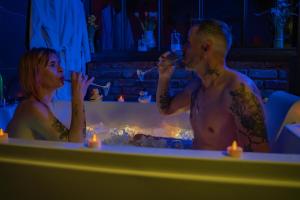 a man and woman sitting in a bathtub with candles at La Maison Coquine Love Room Balnéo in Béthune