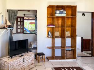 a living room with a tv and a wooden book shelf at Loft NOA'House in Canoa Quebrada