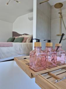 four glass bottles sitting on a wooden tray in a living room at Maison H - Logement de luxe avec jacuzzi privé et home cinéma immersif in Herstal