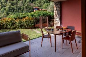 a patio with a table and chairs and a couch at Le Pergole Aloha - Menaggio by LoveComo in Menaggio