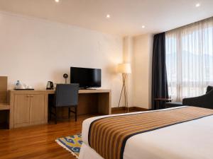 a hotel room with a bed and a desk with a television at Hotel Osel in Thimphu