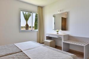 a bedroom with a bed and a desk and a mirror at Makronisos Village in Ayia Napa