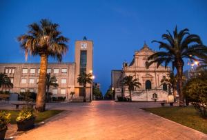 a building with palm trees and a clock tower at LOGGIATO HOUSE-Ispica in Ispica