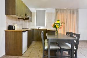 a kitchen with a table with chairs and a vase of flowers at Makronisos Village in Ayia Napa