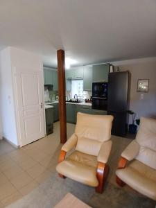 a living room with two chairs and a kitchen at L'Escale Orléans Chambres d'hôtes in Orléans +9 photos