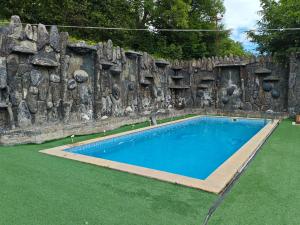 a swimming pool in front of a stone wall at Family Villa with Pool in Əski İqrığ