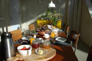 MOoij Bed en Breakfast في أوآيْ: طاولة طعام مع طعام وفواكه عليها