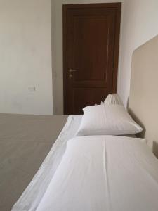 a white bed with white sheets and a brown door at Il Gelsomino in Foligno