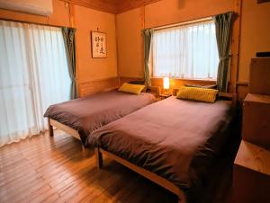 two beds in a room with windows and wooden floors at Lantern Cottage Izukogen in Ito +36 photos