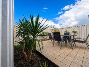 a patio with a table and chairs and a palm tree at Champion Bay Coastal Stay in Geraldton