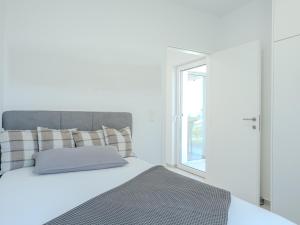 a white bedroom with a bed and a window at Apartment Rahat in Ližnjan
