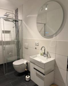 a bathroom with a toilet and a sink and a mirror at Dünenhaus Souterrain Strandallee 3 in Timmendorfer Strand