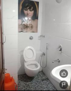 a bathroom with a toilet and a poster of a woman at Amith Comforts near to Railway Station in Mysore