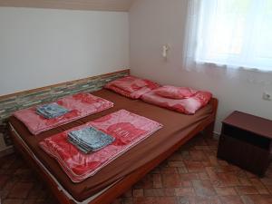 a bedroom with two beds with red sheets and a window at Árvácska Nyaraló in Balatonmáriafürdő +15 photos