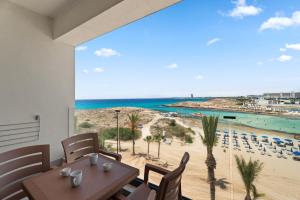 a dining room with a table and a view of the beach at Kritamo Suites Sandy Bay in Ayia Napa