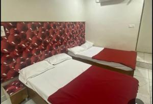 a bedroom with two beds and a red headboard at Amith Comforts near to Railway Station in Mysore +6 photos