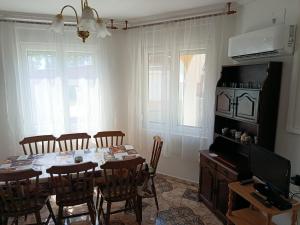 a dining room with a table with chairs and a television at Árvácska Nyaraló in Balatonmáriafürdő