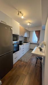 a kitchen with white cabinets and a black refrigerator at ZBI Apartament in Oradea