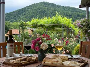 a wooden table with wine glasses and bread and flowers at Guest House Gardenia & Wine Cellar in Lagodekhi