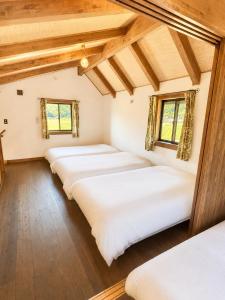 a row of beds in a room with wooden ceilings at Setouchi Retreats Sera Highlands in Egi