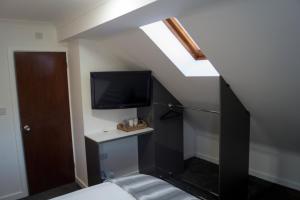 a room with a bed and a tv on the wall at Kirks Korner Motel in Scunthorpe