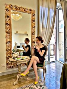 a woman sitting in a chair in front of a mirror at Kèramos Luxury Rooms in Sciacca