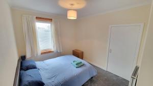 a bedroom with a blue bed and a window at Stornoway Stays Apartment in Stornoway