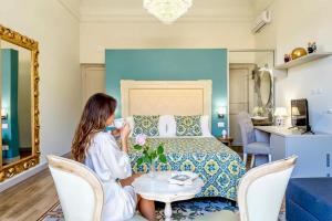 a woman sitting at a table in a hotel room at Kèramos Luxury Rooms in Sciacca