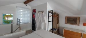 a white bedroom with a tub and a window at Gîte La Cour Cachée in Saulx-en-Woëvre