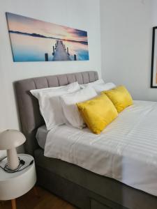 a bed with white sheets and yellow pillows at Lovely apartment Branko Rabac with balcony and parking in Rabac