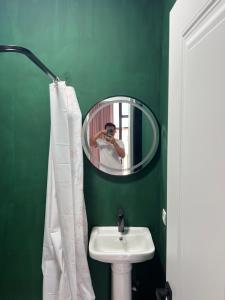 a man taking a picture of a bathroom with a mirror at aROYAL in Cholpon-Ata