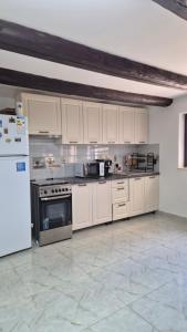 a large kitchen with white cabinets and a refrigerator at Piatra Humorului in Mănăstirea Humorului +8 photos