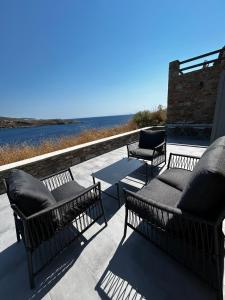 a patio with chairs and tables and the ocean at Salty Rock - Kythnos Suite in Kithnos