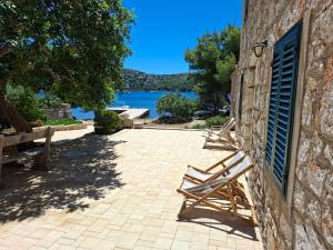 two wooden benches sitting next to a stone building at House Antica in Lastovo
