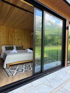 a bedroom with a bed and a large window at Villa Ujëvara e vogël in Theth