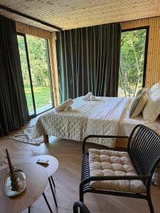 a bedroom with a bed and a chair and windows at Villa Ujëvara e vogël in Theth