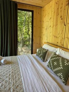 a bed with two pillows in a room with a window at Villa Ujëvara e vogël in Theth