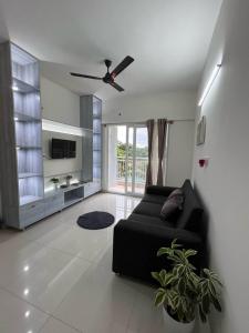 a living room with a black couch and a ceiling fan at Beruru Homes- 2BHK Apartment near Bengaluru Airport in Devanhalli