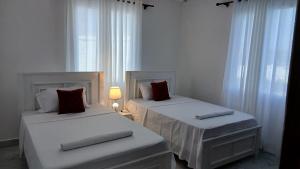 two beds in a room with white curtains and a lamp at Hermit Homes in Mombasa