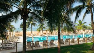 a pool with chairs and palm trees next to the beach at Casa Del Papa Resort in Ouidah