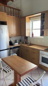 a kitchen with wooden cabinets and a table and a refrigerator at Little Summer Chalet in Saronida