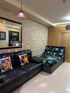 a living room with a leather couch and a table at Shell Residences MOA&NAIA by-Sandy in Manila